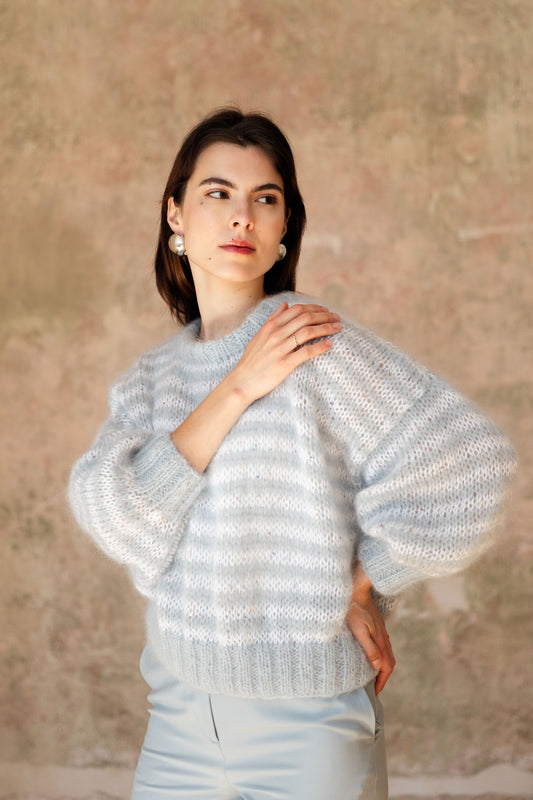 A woman wearing a hand-knitted mohair sweater with soft tonal stripes and floral sequins.