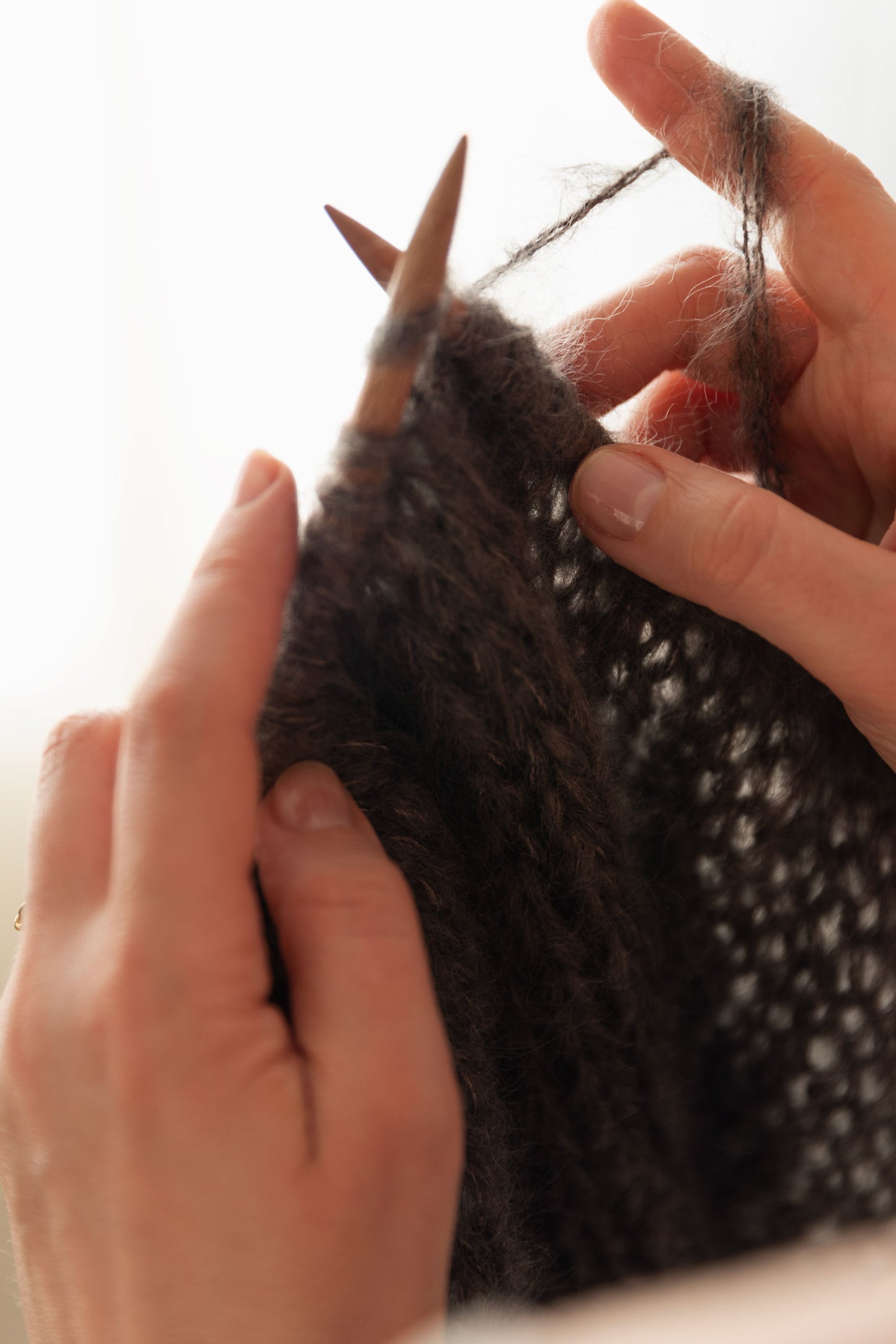Close-up of hands knitting with mohair and wooden needles