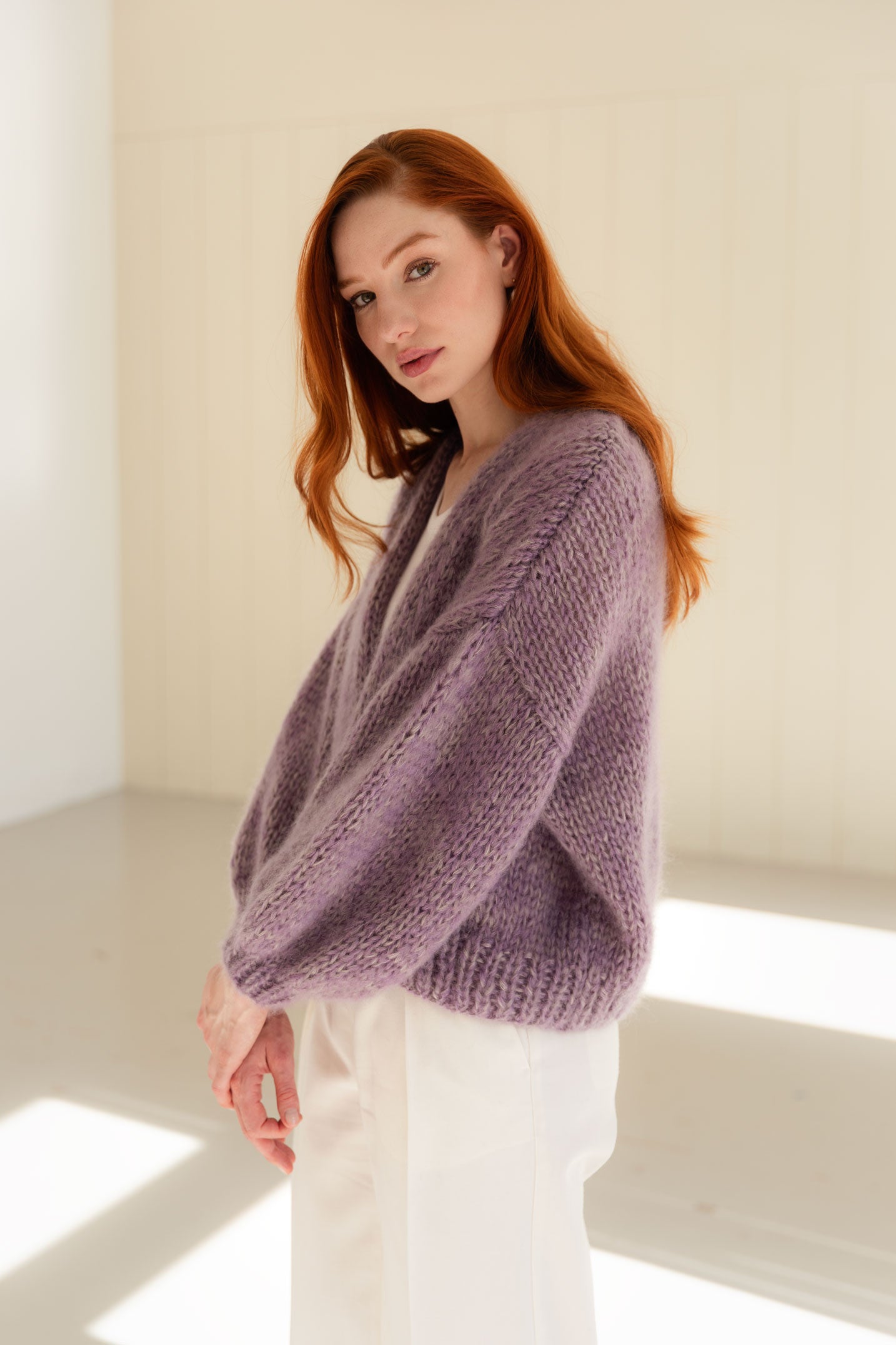 Woman wearing a purple mohair cardigan in a bright room