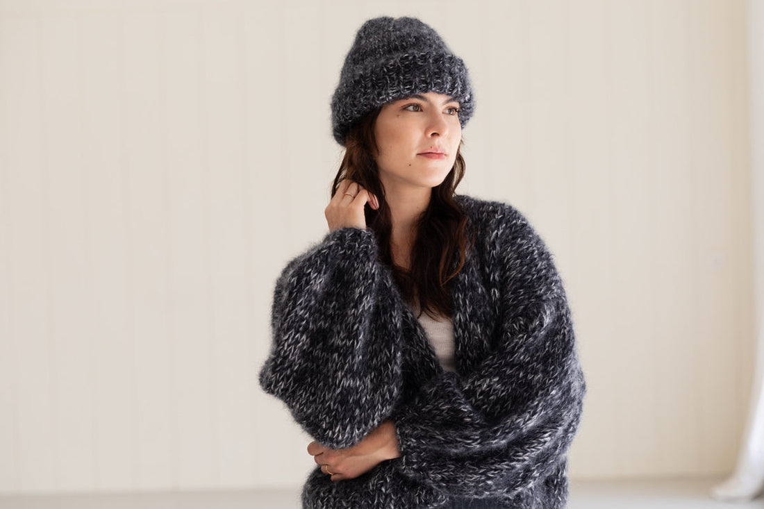 Woman wearing a chunky mohair cardigan in moulinee black, paired with a matching beanie