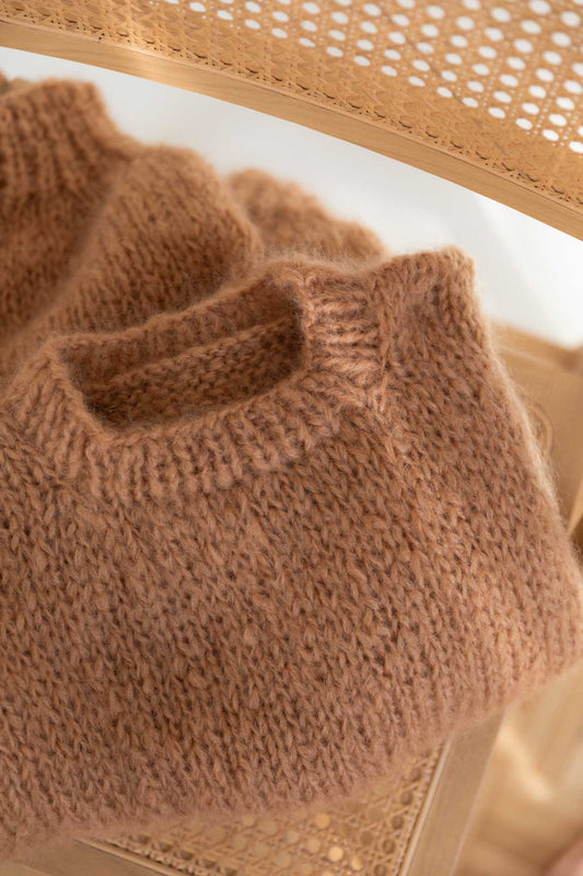 A textured brown mohair sweater resting on a chair