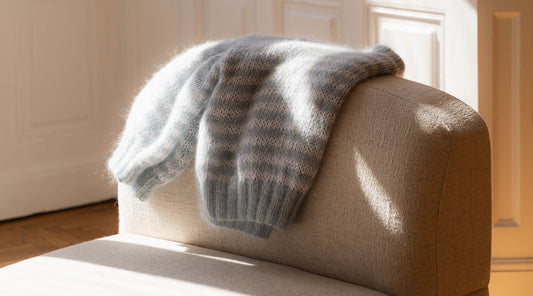 A white and blue stripes mohair sweater resting on a cream sofa