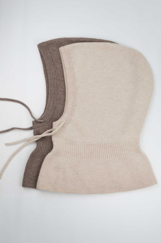 Side view of two 100% Mongolian cashmere balaclavas in beige and brown, showing the adjustable drawstring and wide shoulder drape.
