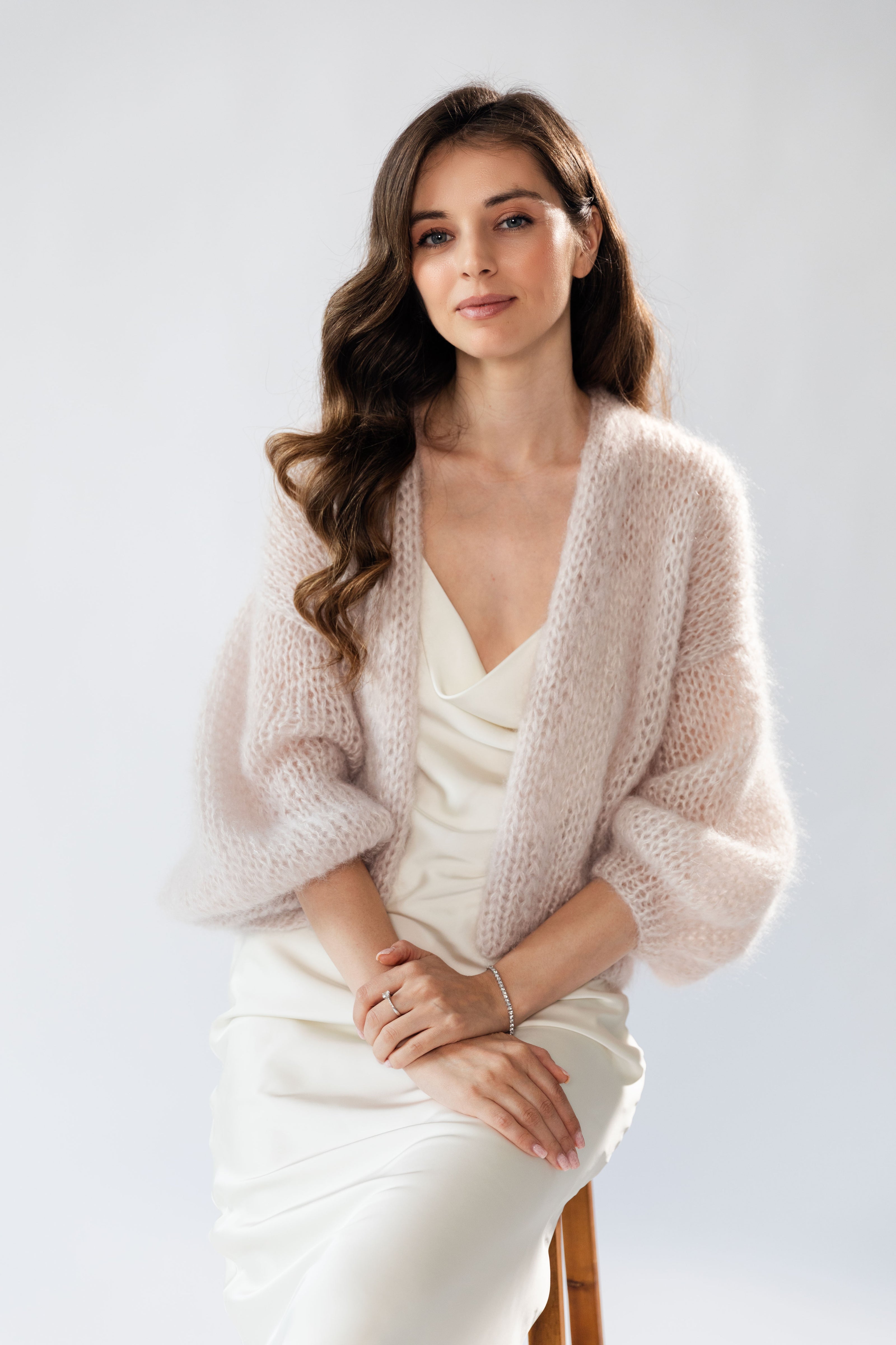Woman wearing a dust rose mohair cardigan over a white silk dress