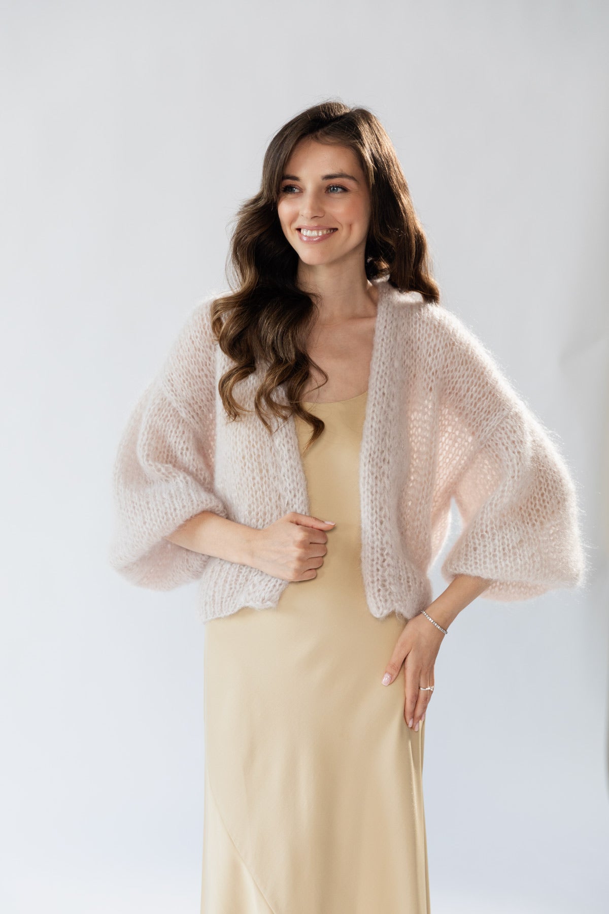 A woman wearing an airy mohair cardigan over a beige slip dress.