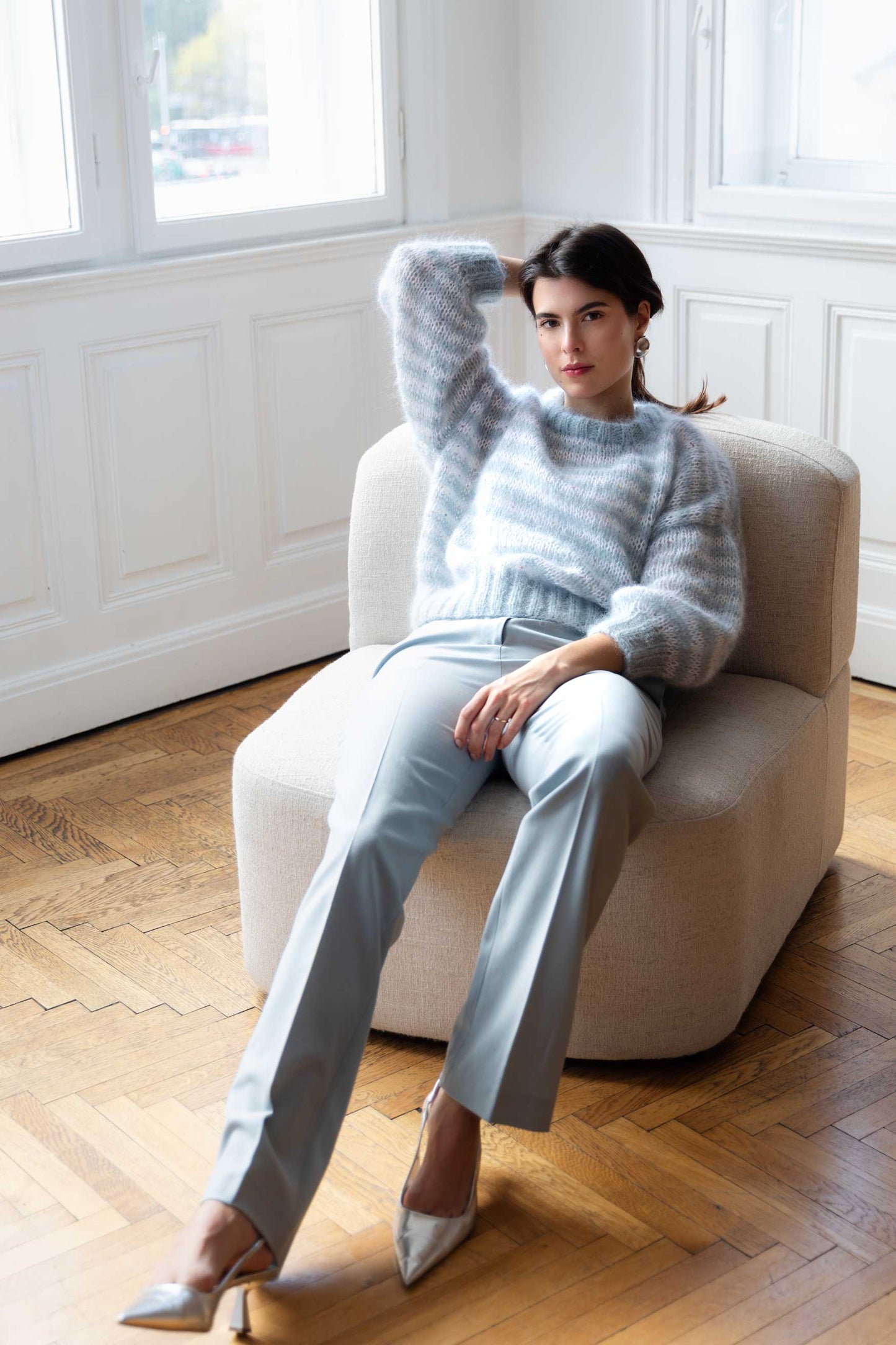 Woman wearing a striped blue and white mohair sweater, sitting on a sofa
