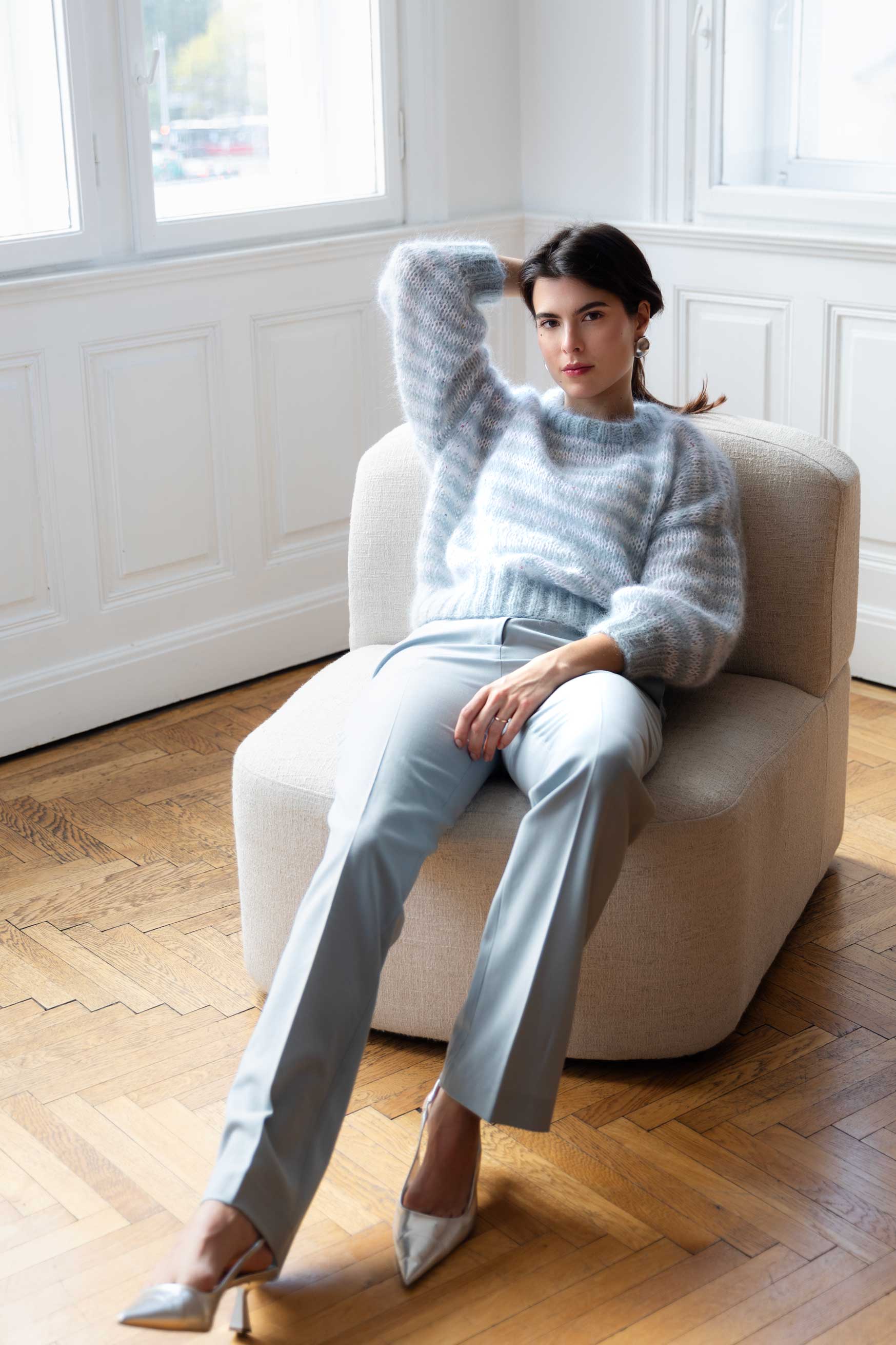 Woman wearing a striped blue and white mohair sweater, sitting on a sofa