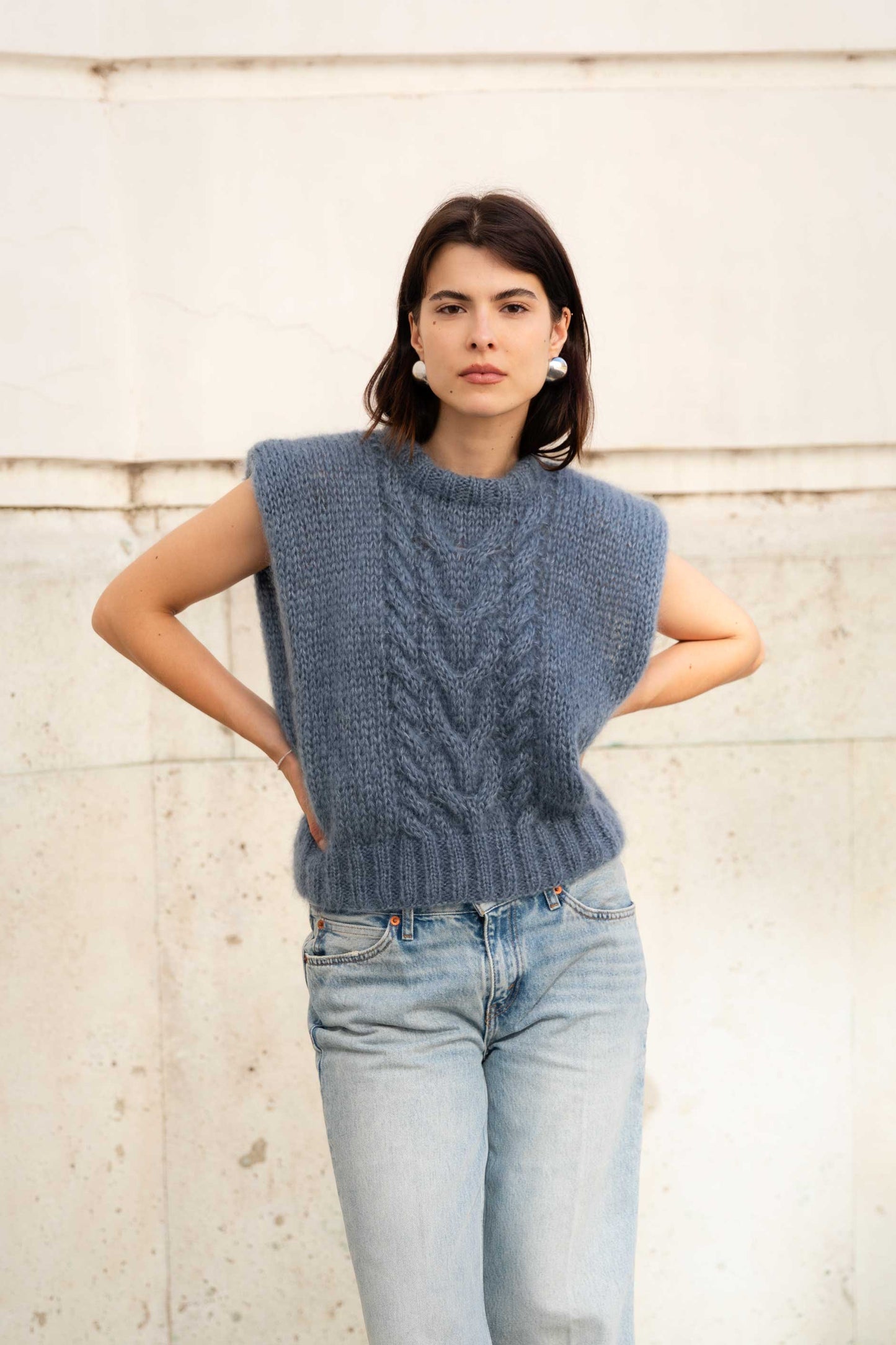 Woman wearing a blue mohair vest with a cable knit pattern.