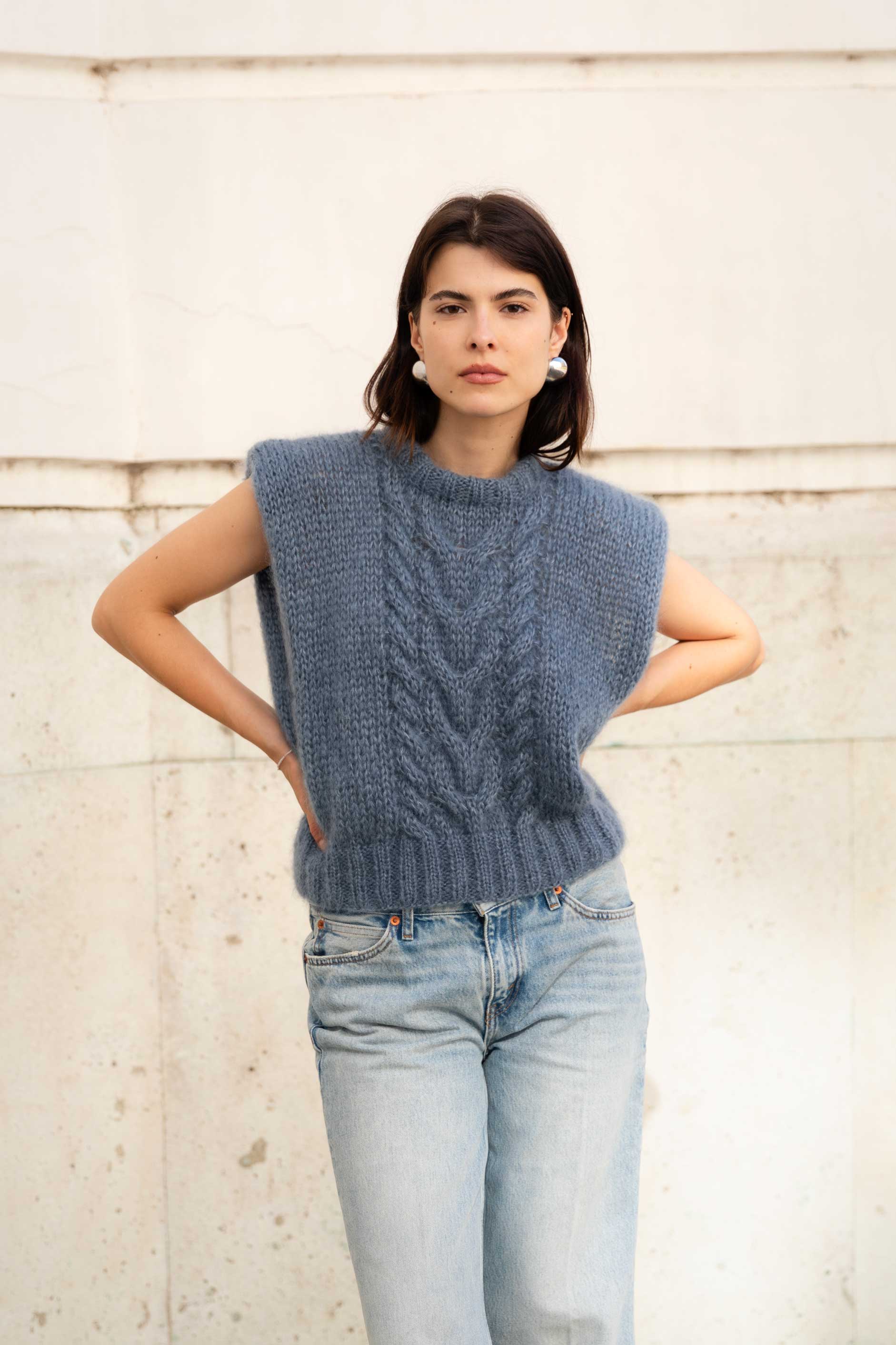 Woman wearing a blue mohair vest with a cable knit pattern.