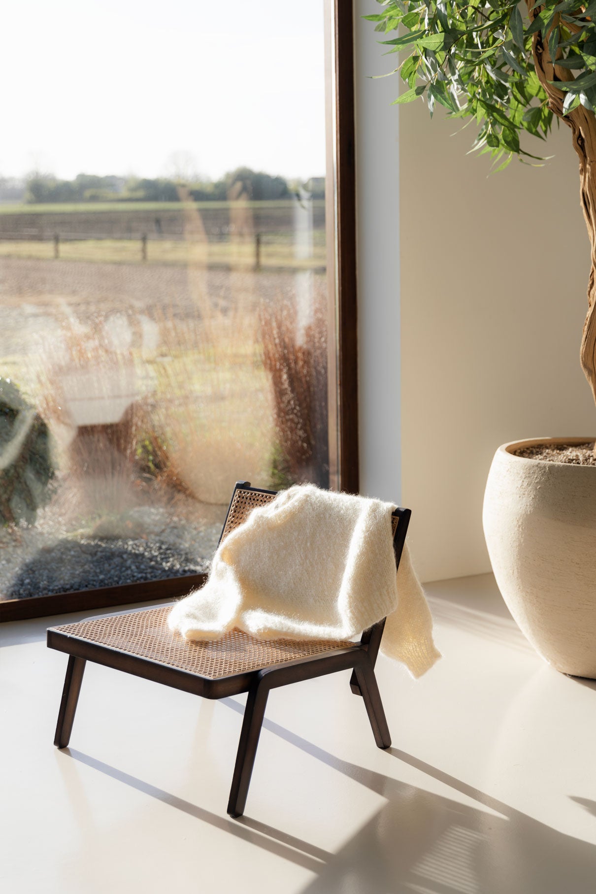 Mohair sweater resting on a wooden chair near a big window