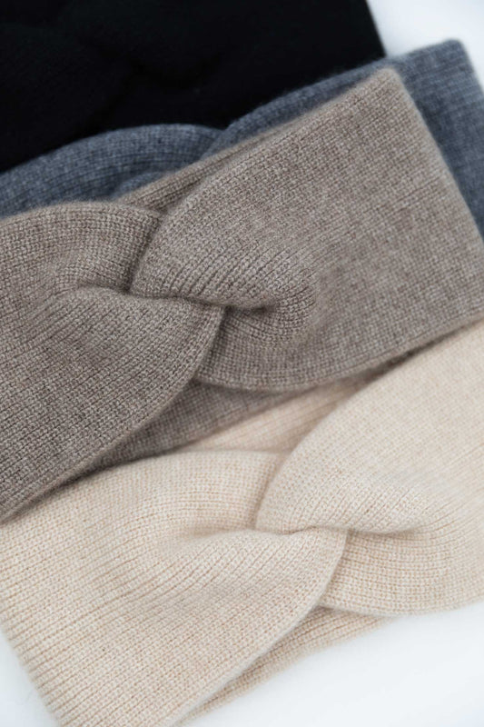 Close-up of knitted cashmere headbands in slate grey, oatmeal, and taupe on a white background
