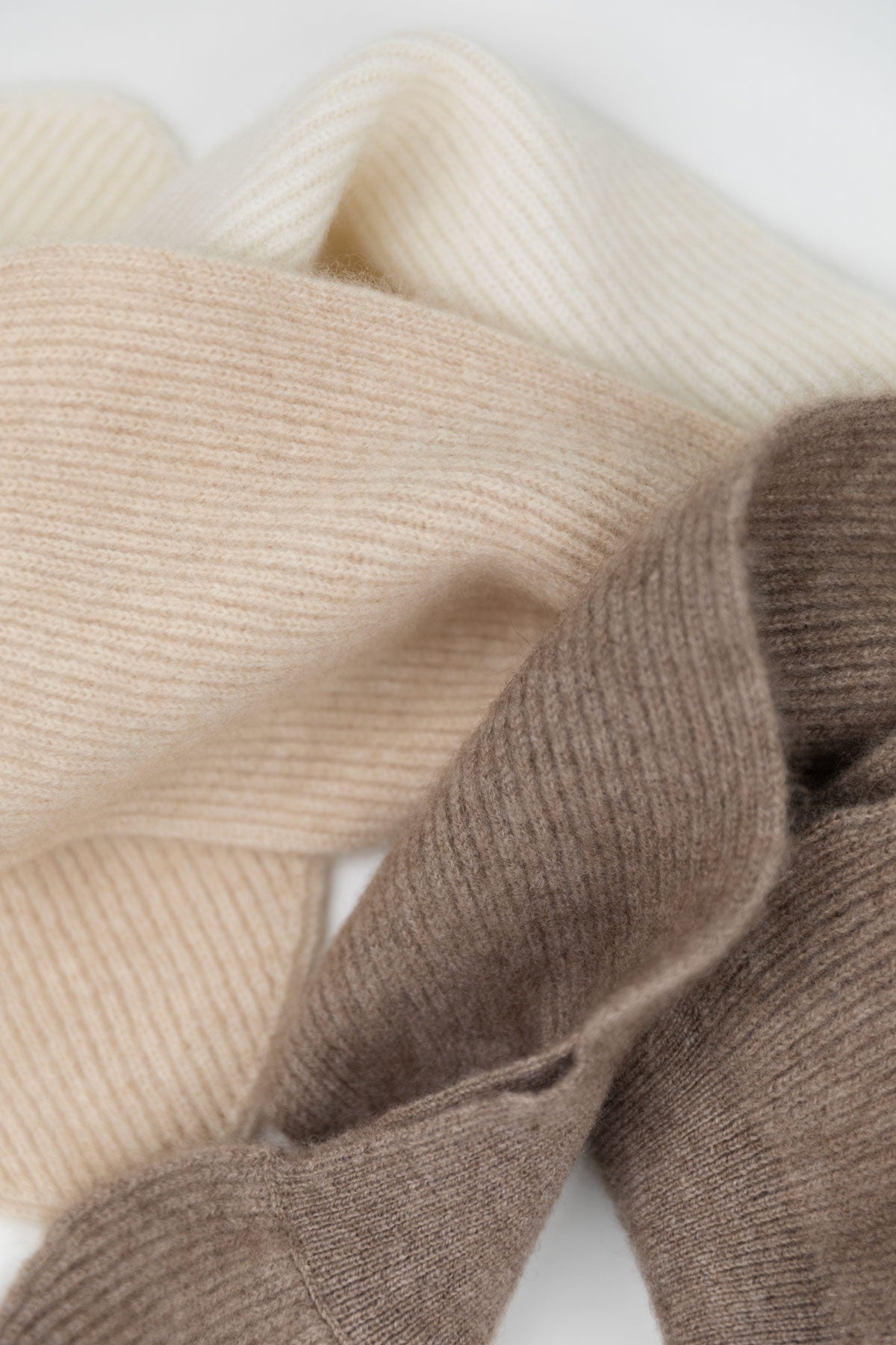 Close-up of cashmere fabric in cream, beige, and taupe-brown on a white background.