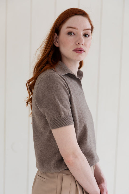 Woman wearing a taupe cashmere polo shirt against a white background