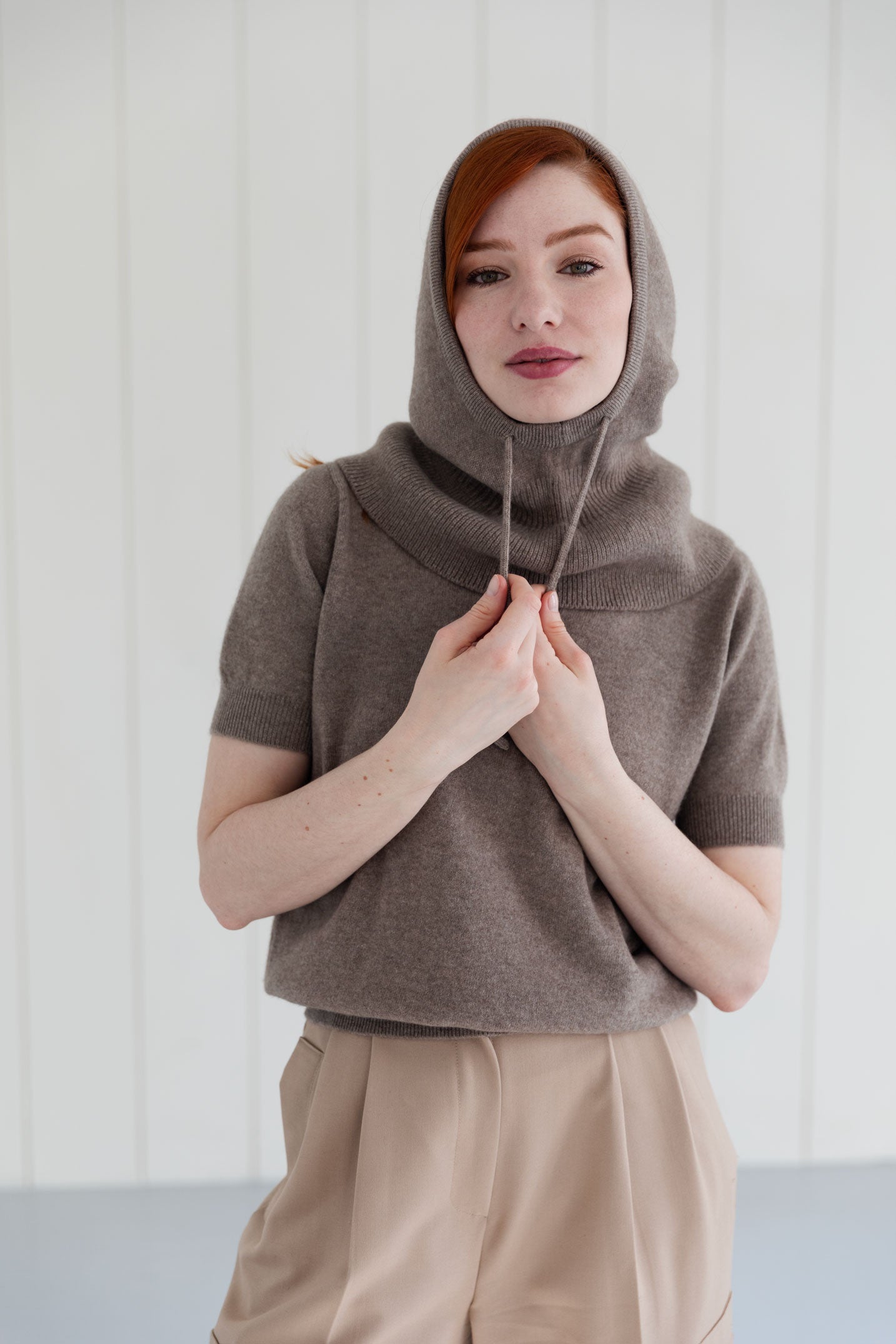 Woman wearing a taupe cashmere balaclava, and matching cashmere short sleeve top
