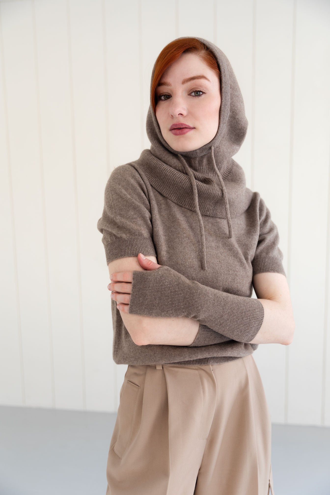 Woman wearing a taupe cashmere balaclava, and matching cashmere arm warmers and cashmere short sleeve top
