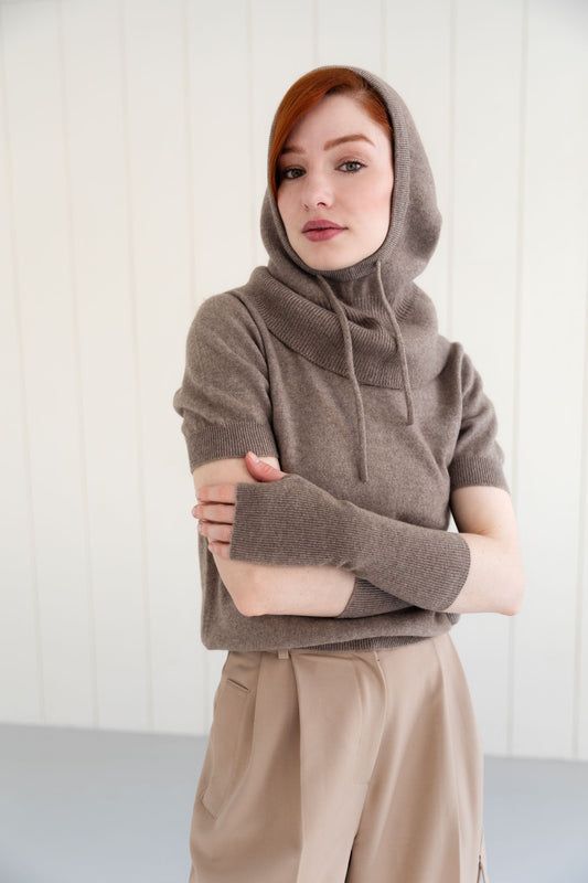 Woman wearing a taupe cashmere balaclava, and matching cashmere arm warmers and cashmere short sleeve top