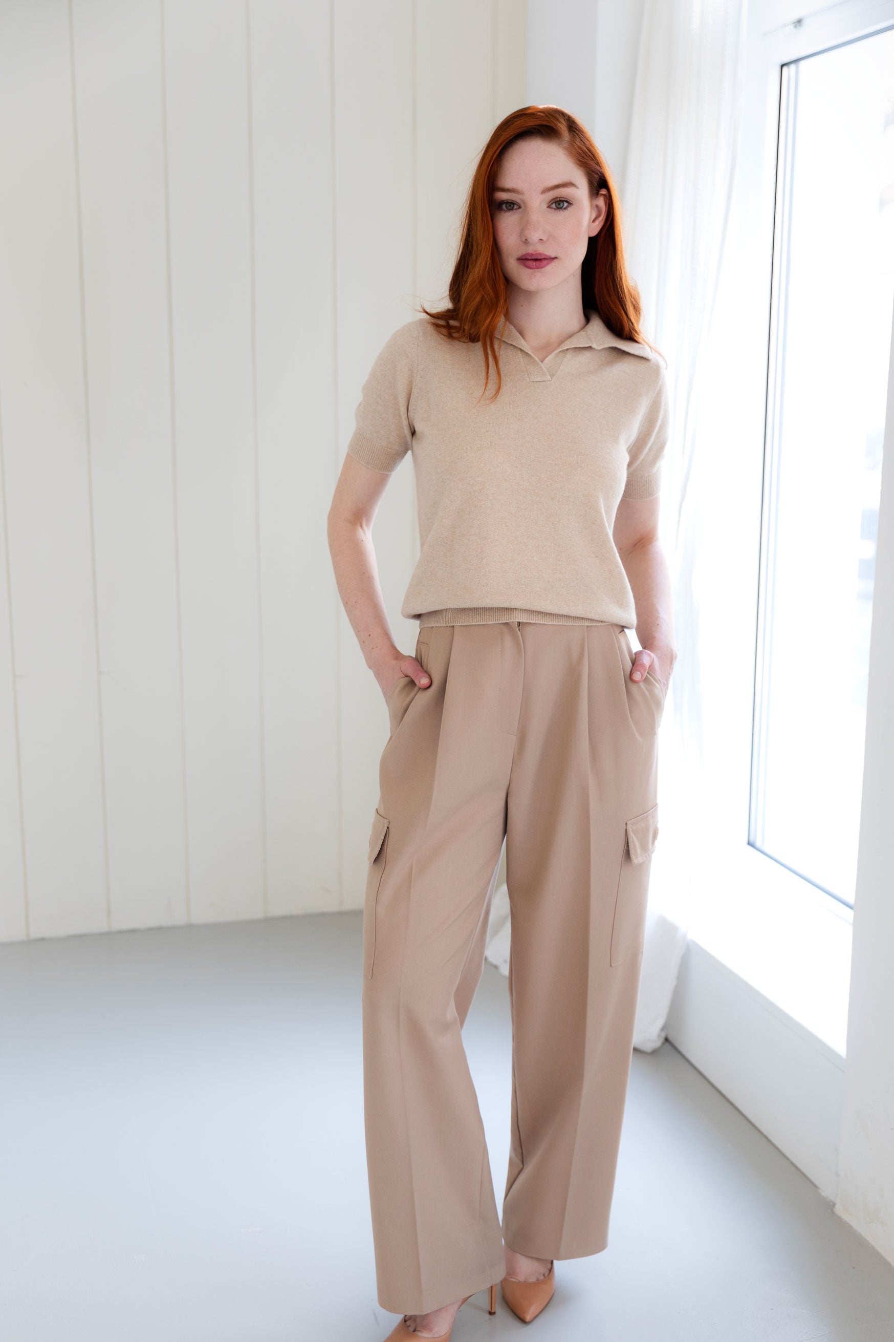 Woman wearing a beige cashmere polo shirt and beige cargo pants
