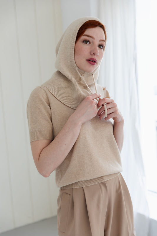 Woman wearing a beige cashmere balaclava, and matching cashmere short sleeve top