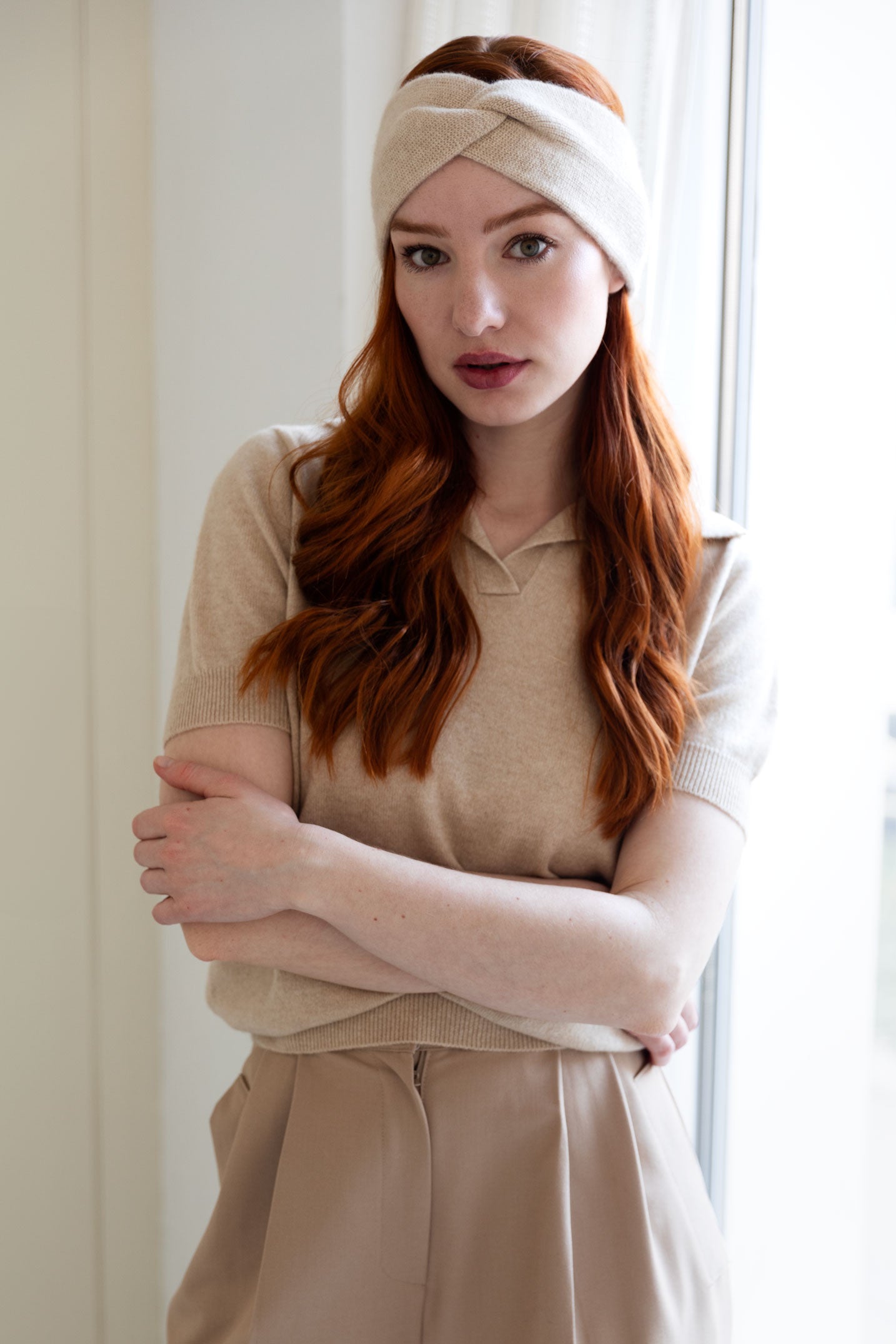 Woman wearing a beige cashmere headband and matching cashmere sweater.