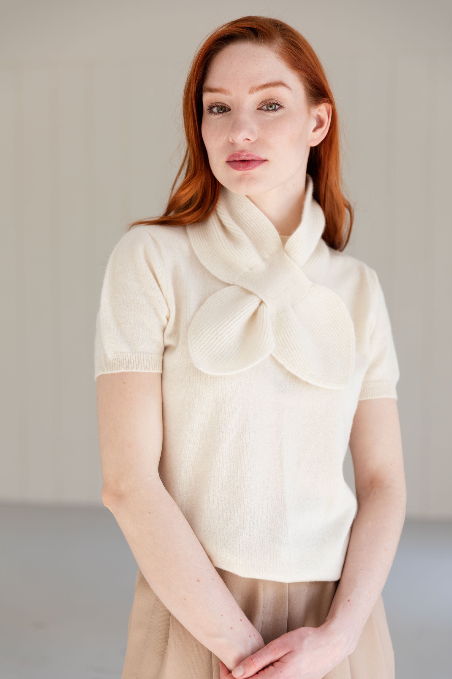Woman wearing a white cashmere mini scarf with matching cashmere top.