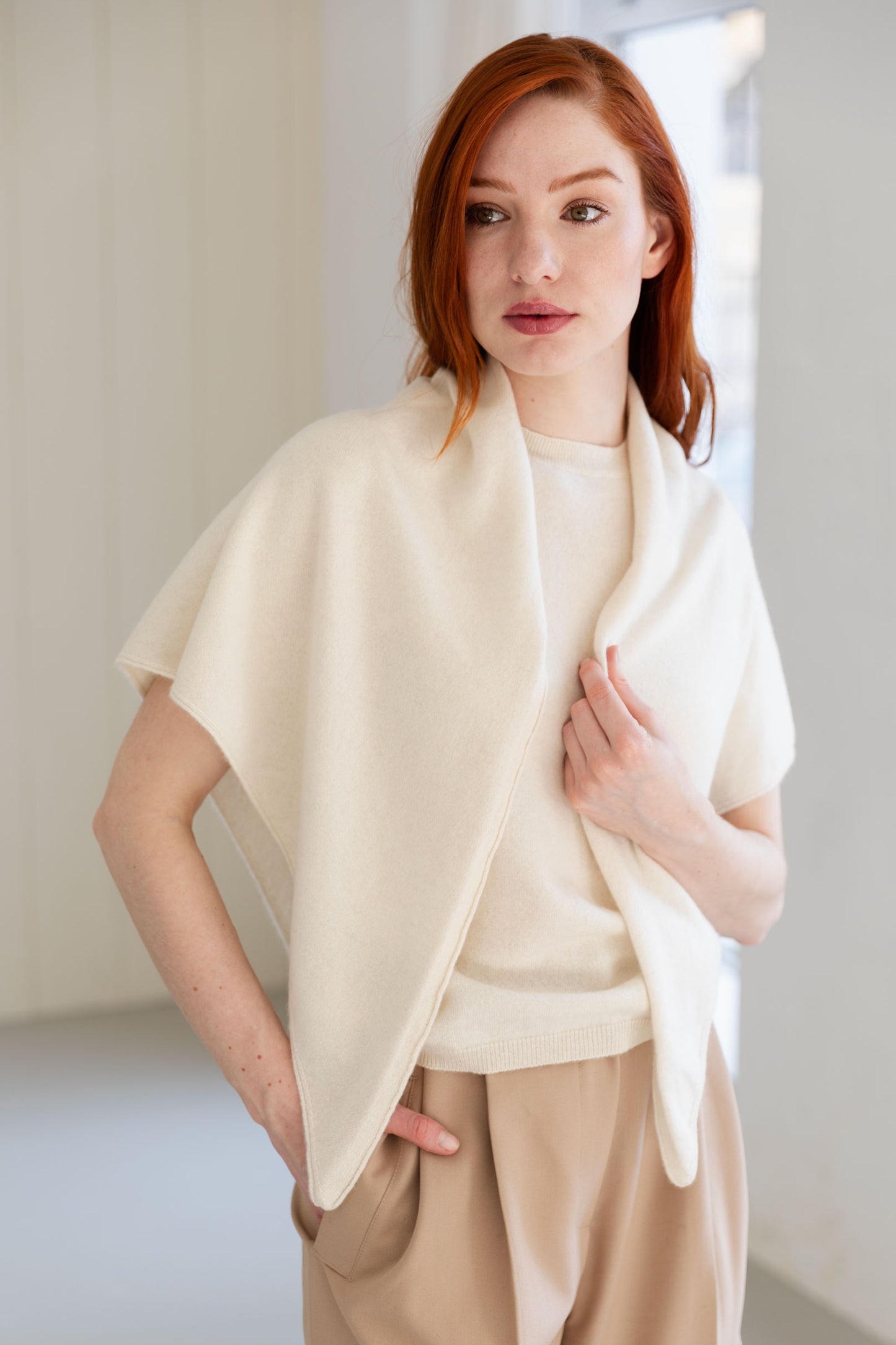 Woman wearing a cream-colored cashmere triangle scarf and beige pants