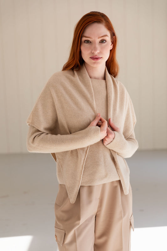 Woman wearing a beige cashmere triangle scarf over a matching sweater 