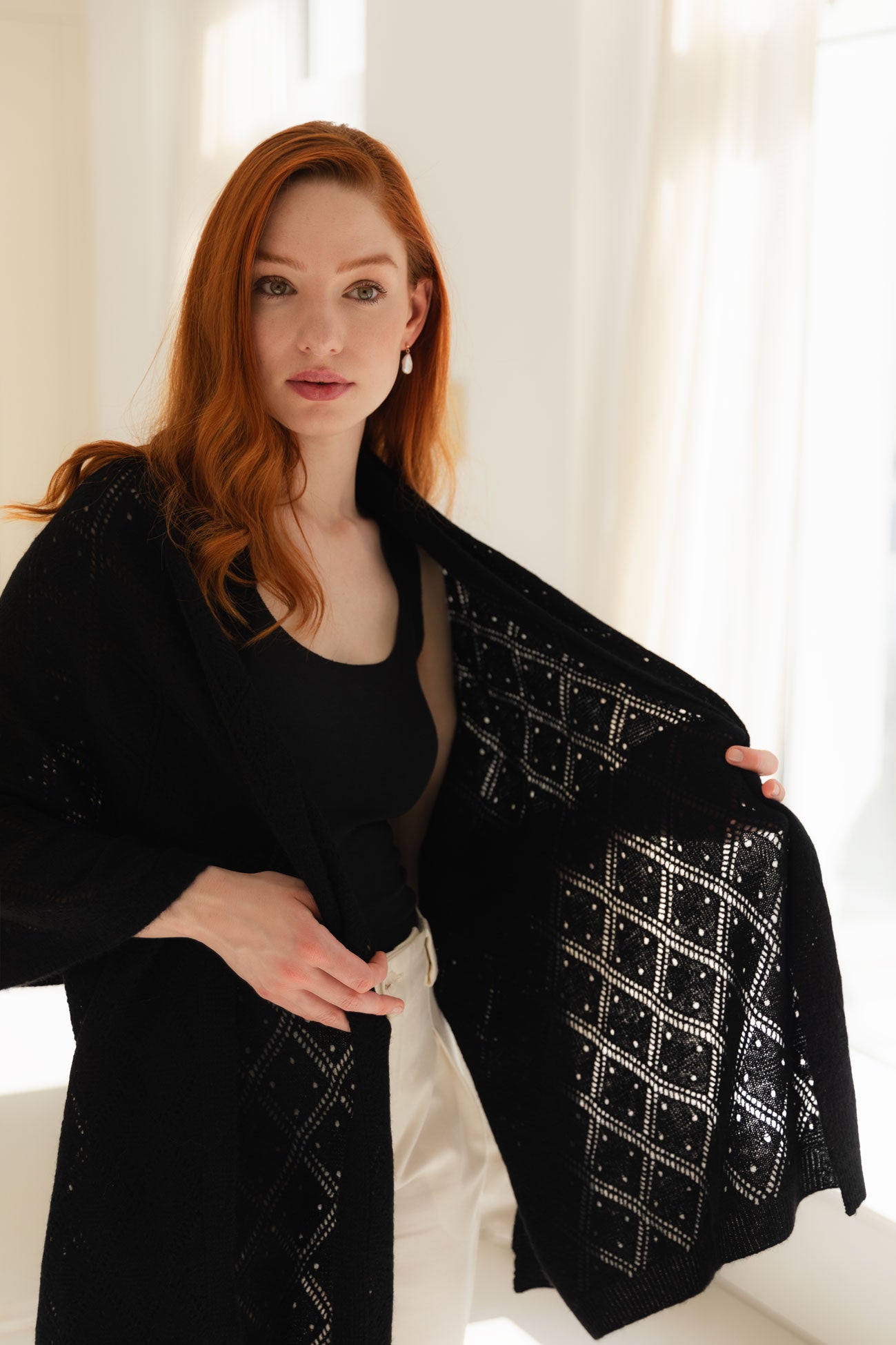 Woman wearing a black lace cashmere shawl in a bright room.