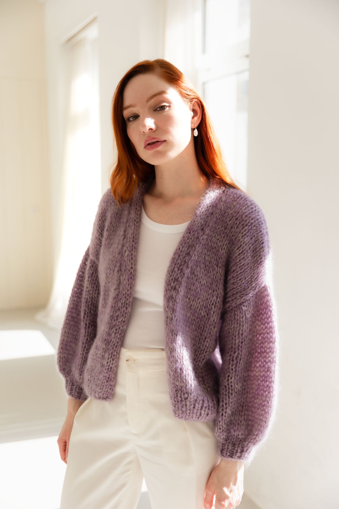 Woman wearing a soft, fluffy purple mohair cardigan in a bright room
