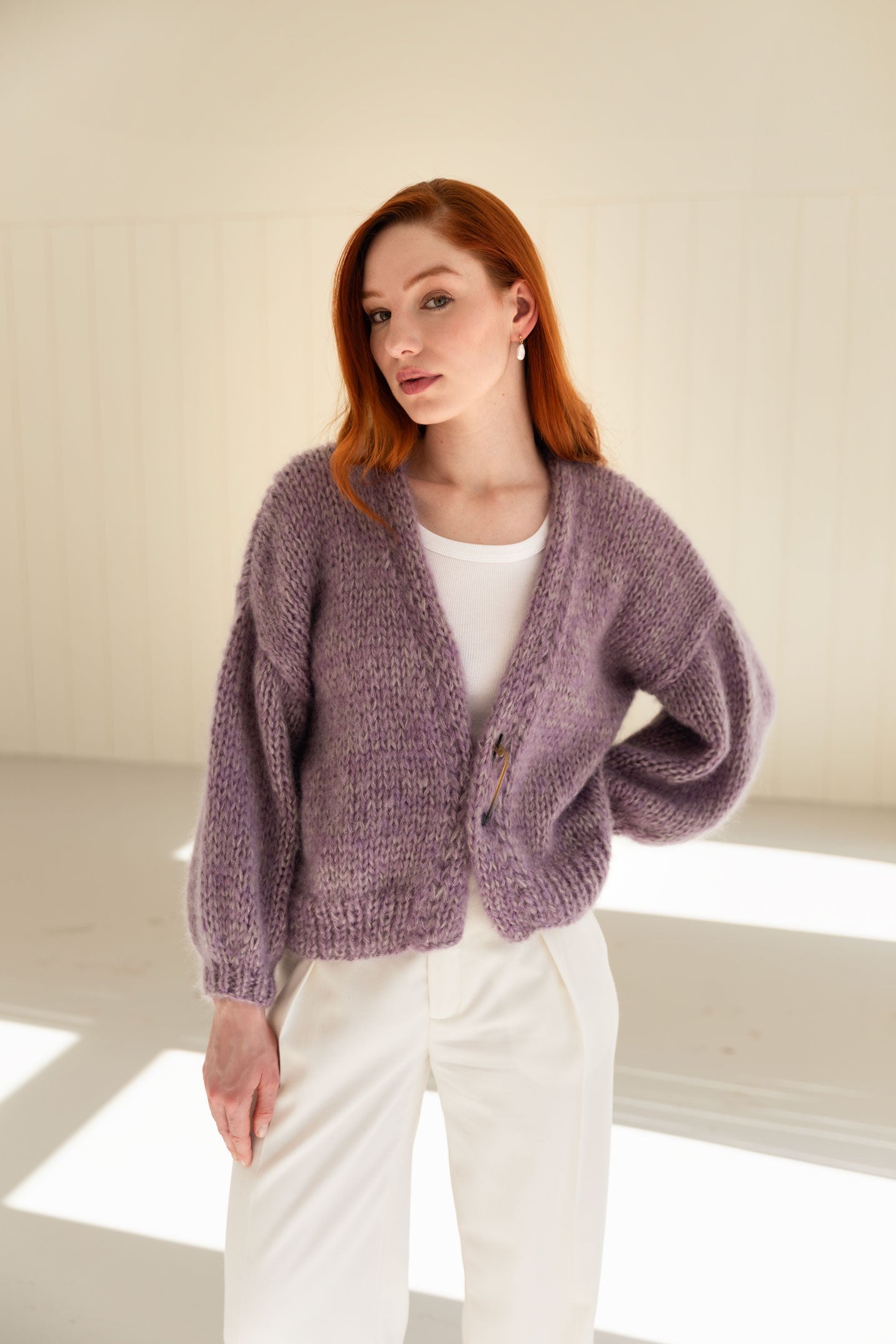 Woman wearing a purple mohair cardigan over a white top and pants