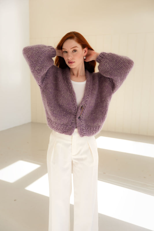 Woman wearing a purple mohair cardigan in a minimal white room