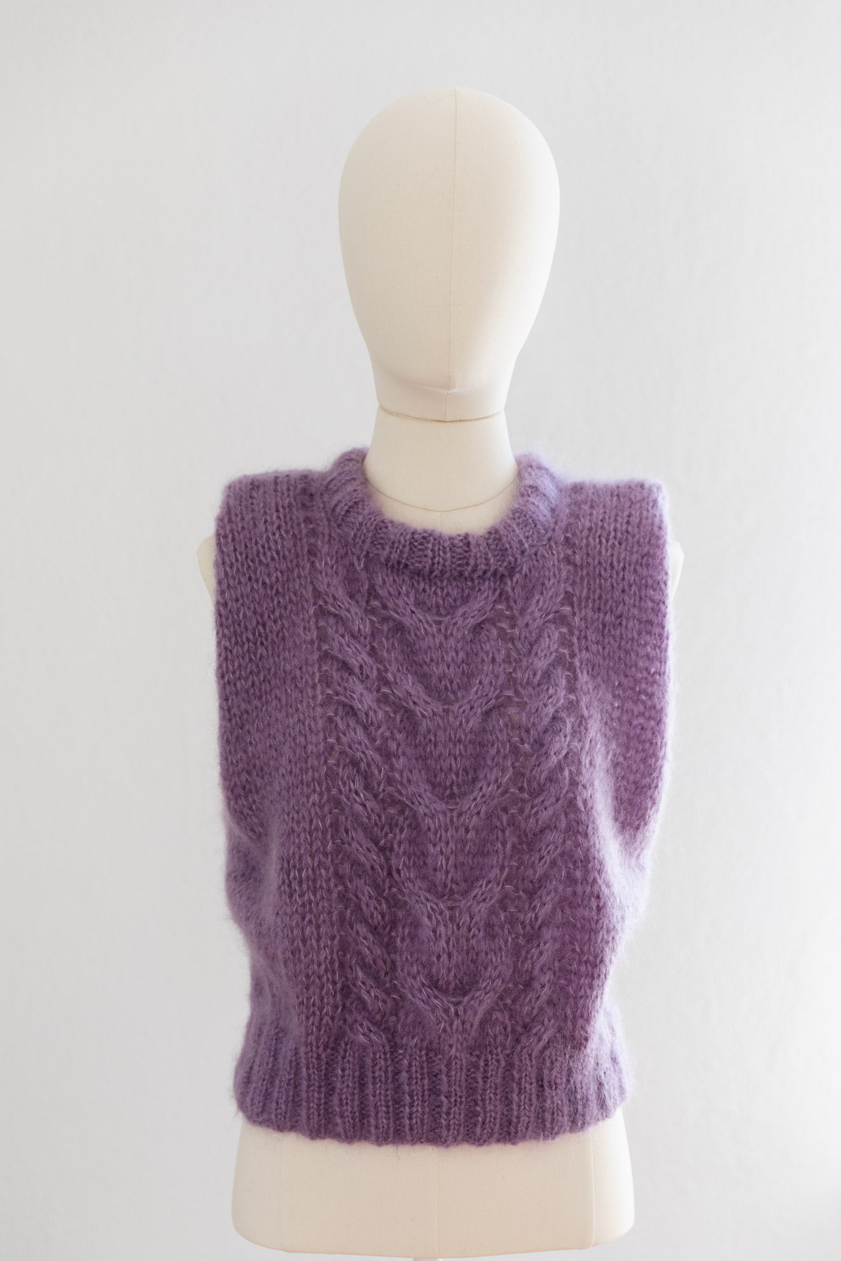 A lavender purple mohair sweater vest displayed on a cream mannequin torso against a light background.