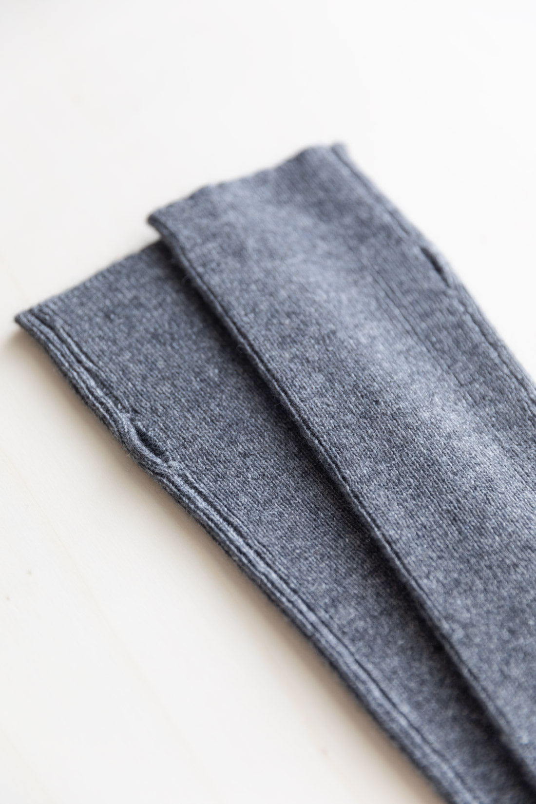 A close-up of cashmere arm warmers in dark grey on a plain white background.