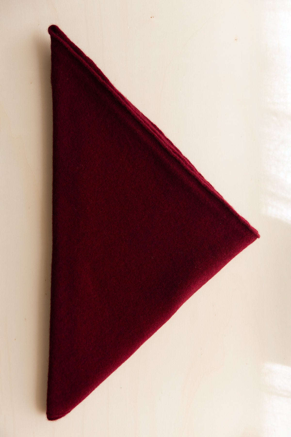 A cashmere triangle scarf in dark cherry displayed on a clean white background.