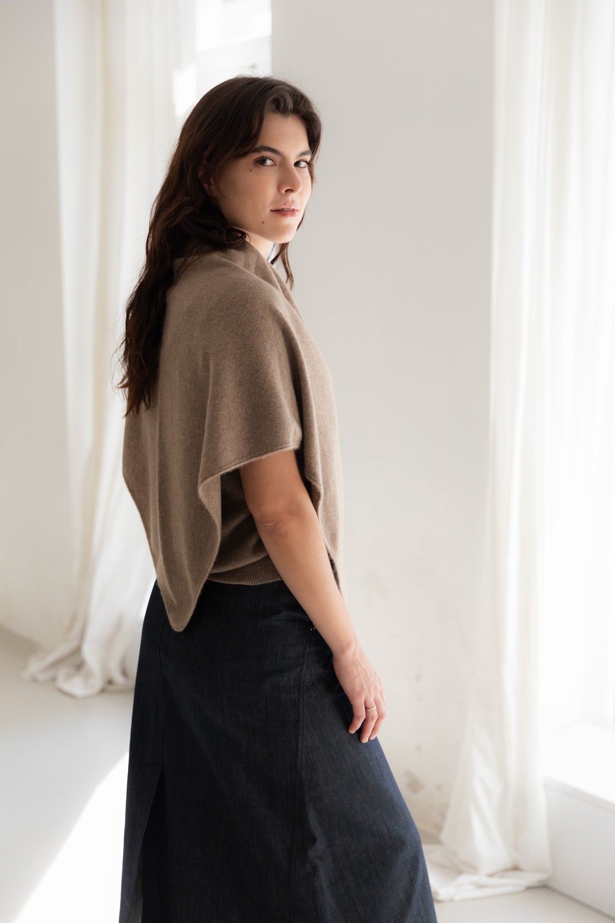 Woman wearing a brown cashmere triangle scarf against a neutral background