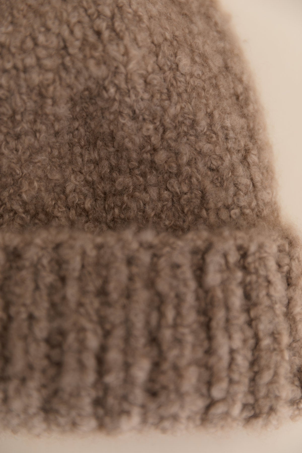 A close-up of a cashmere bouclee beanie in taupe colour.