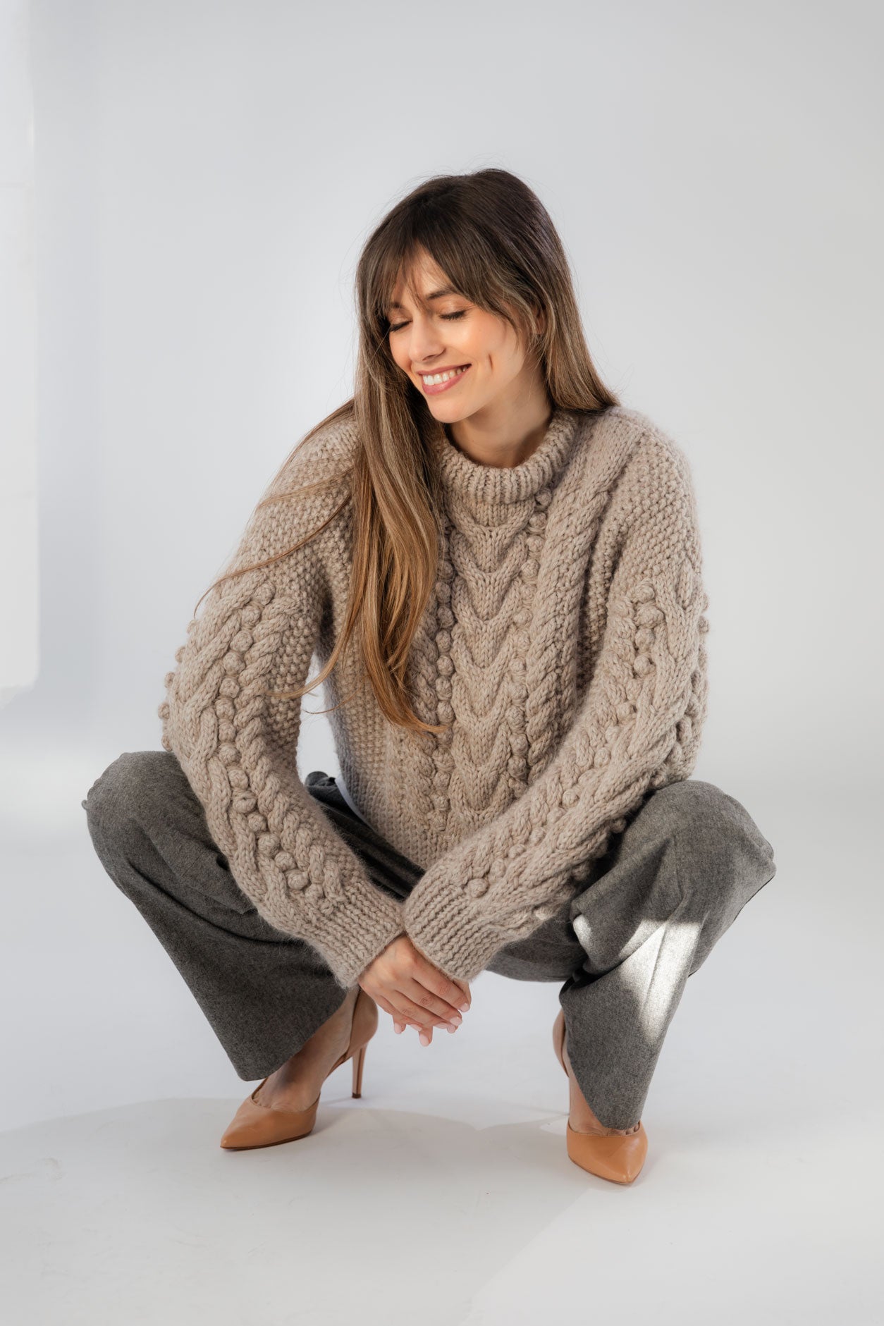 Woman wearing a wool-alpaca cable knit and bubble sweater