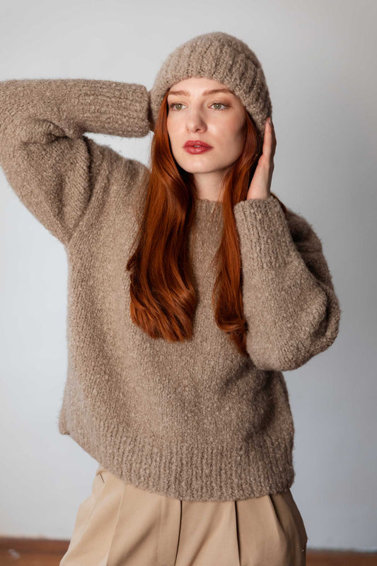 Model wearing taupe bouclé cashmere beanie and sweater, handmade in Salzburg