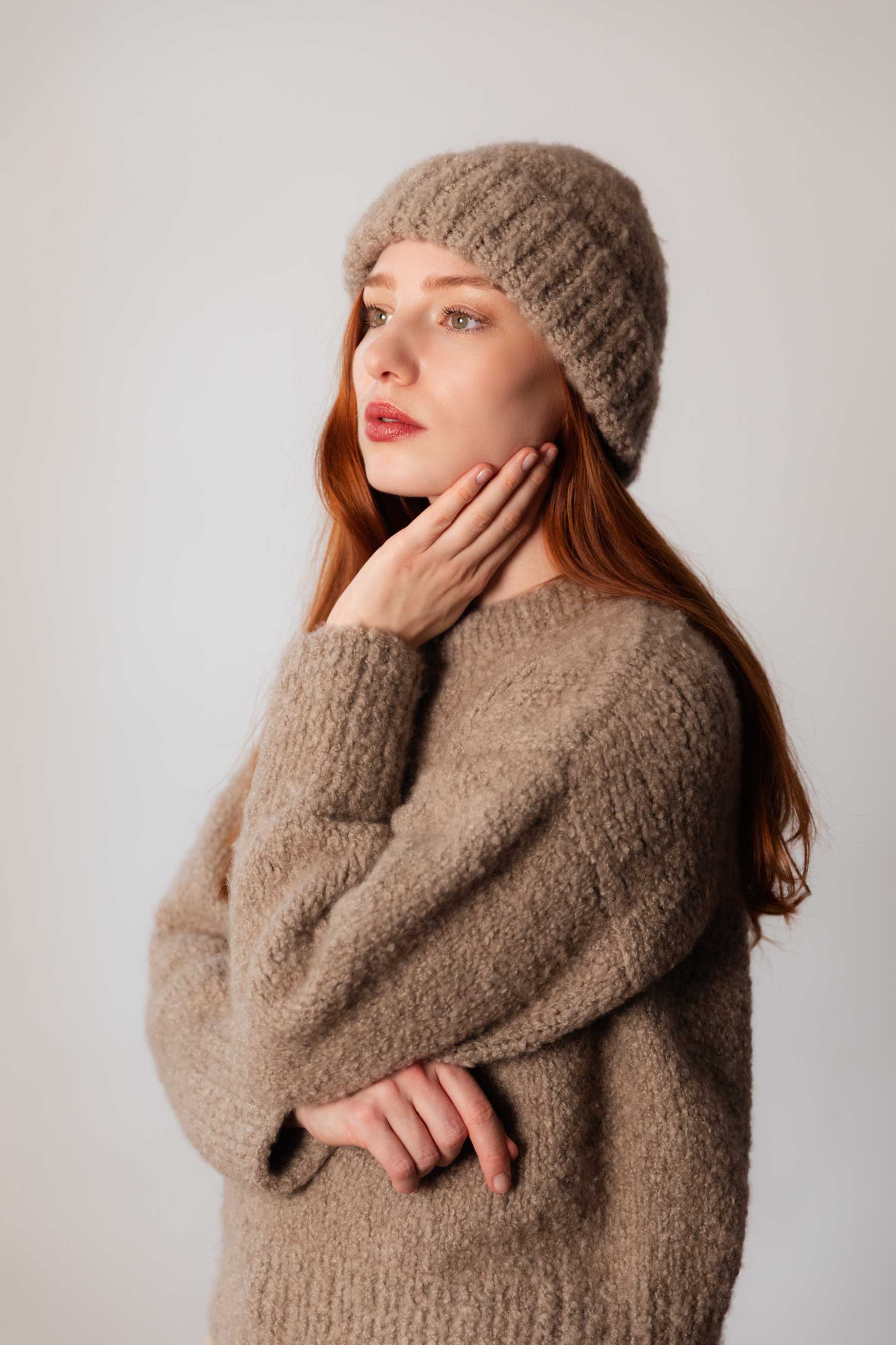 Side view of model wearing taupe bouclé cashmere beanie and sweater, handmade in Salzburg - side view
