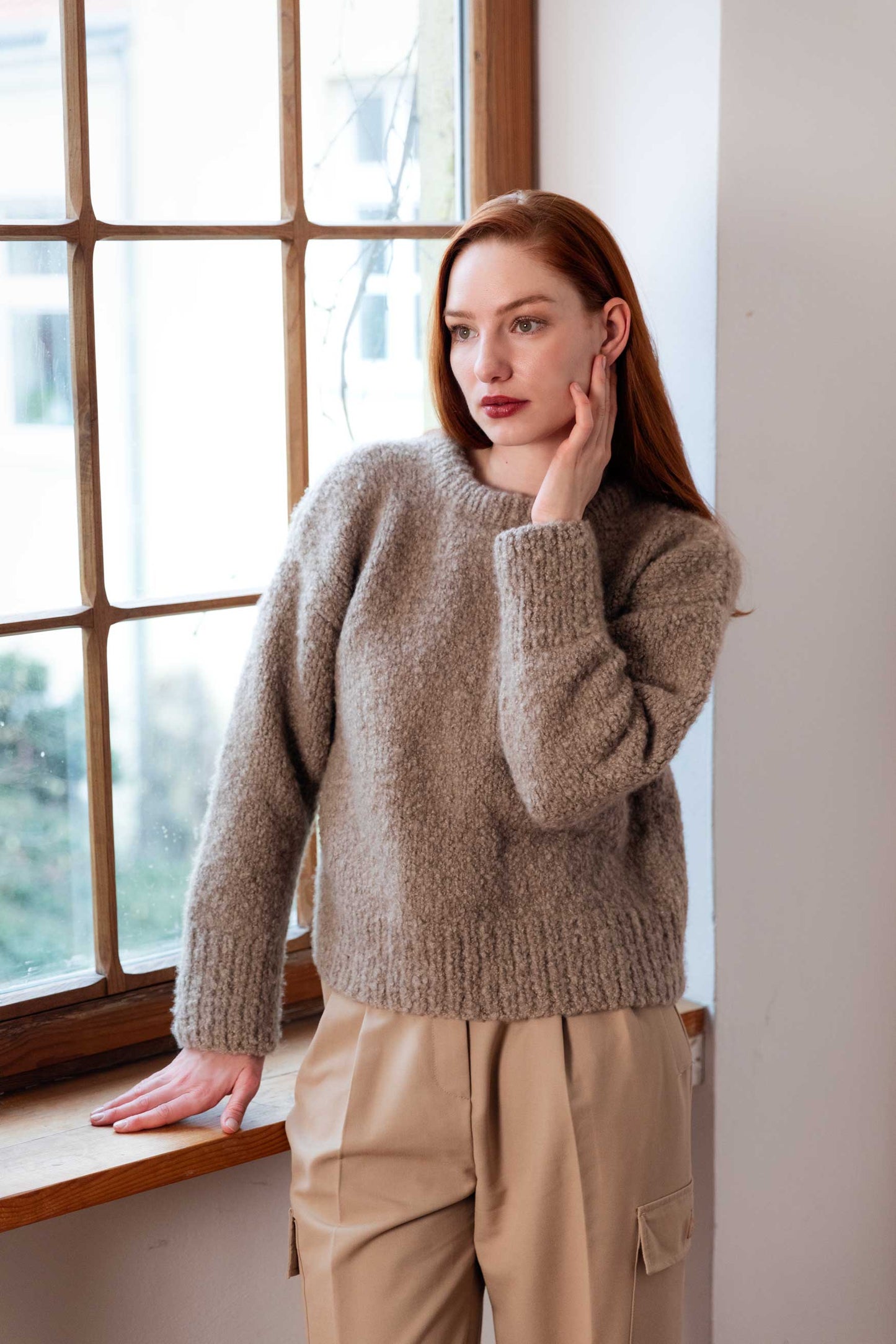 Woman wearing a 100% Mongolian cashmere sweater standing by a window.